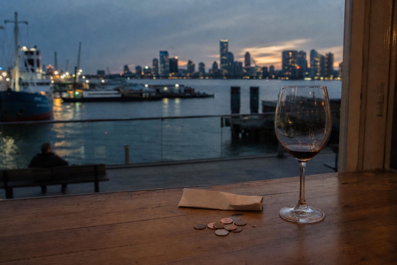 Small euro coins and a folded receipt beside a wine glass on a wooden kitchen table after a meal