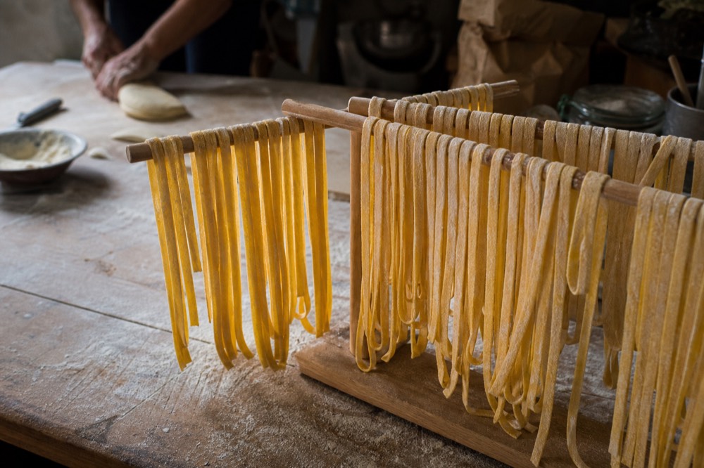 Fresh tagliatelle ribbons dusted with flour on a wooden worktop