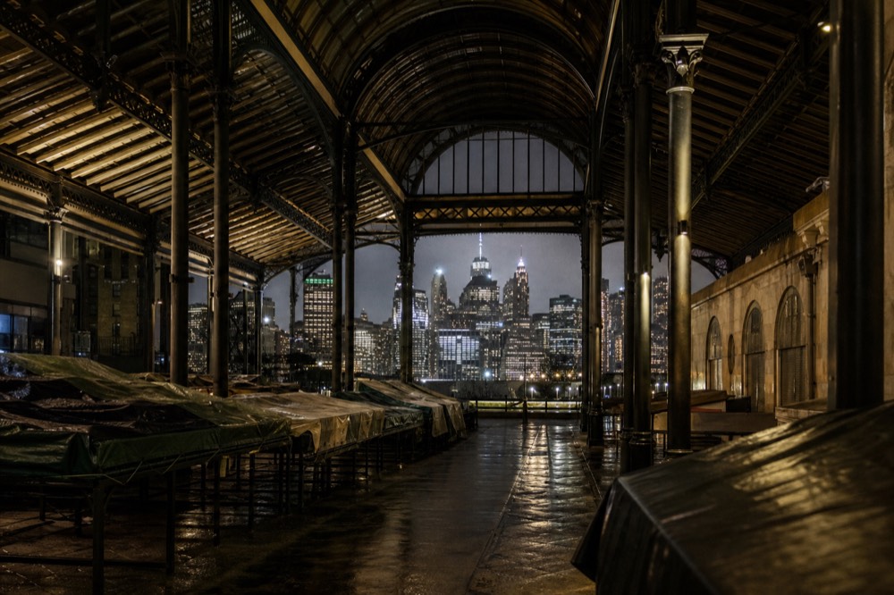 Tall cast-iron columns and an arched glass roof above a Florentine market hall, empty aisles in early morning light
